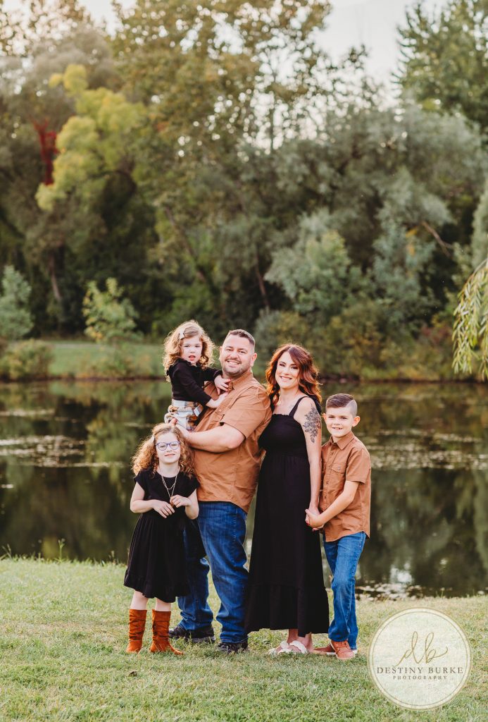 Family posing for family portrait photography session in Chili, NY at Black Creek Park near Rochester, NY