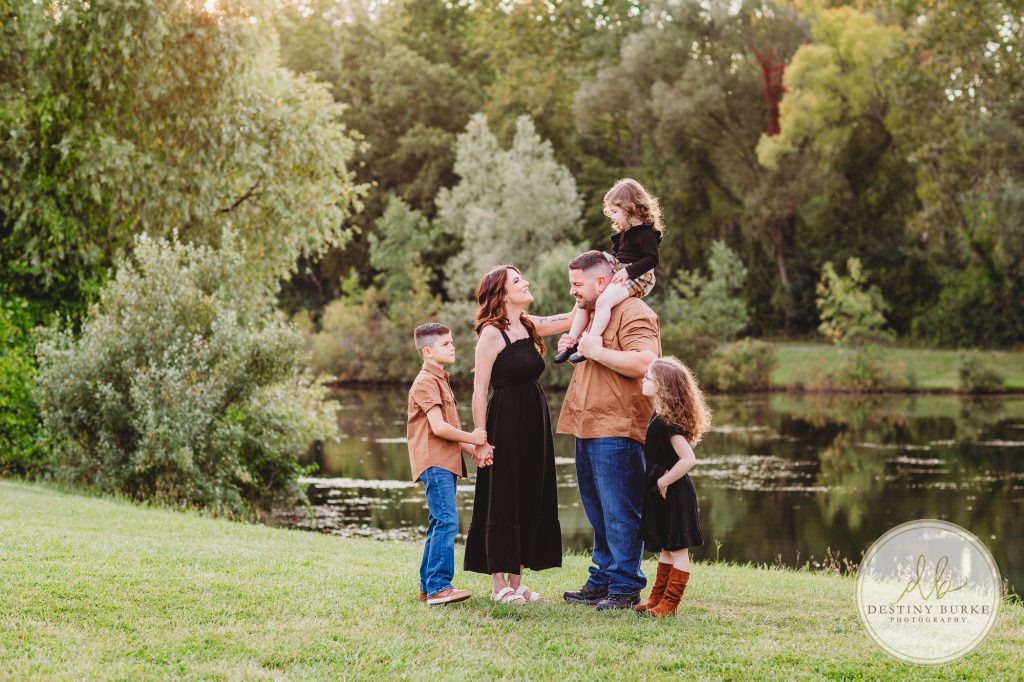 Family posing for family portrait photography session in Chili, NY at Black Creek Park near Rochester, NY