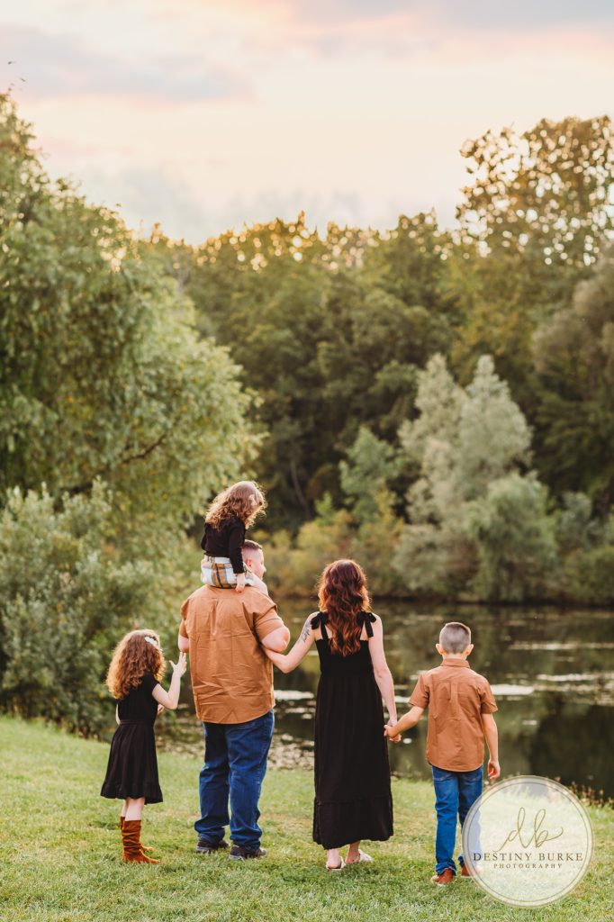 Family posing for family portrait photography session in Chili, NY at Black Creek Park near Rochester, NY