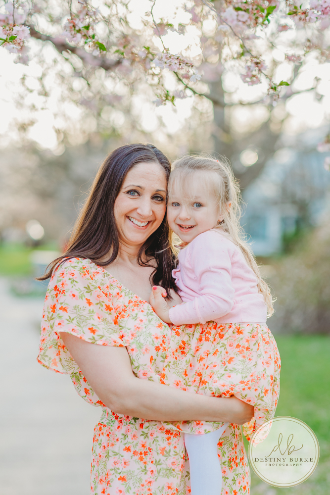 best family photographer near Rochester, NY, at Highland Park, family of 4 under the Cherry Blossom trees, photographed by Caledonia photographer, Destiny Burke Photography at sunset. 6 Month old and 3 year old children with Mom and Dad.