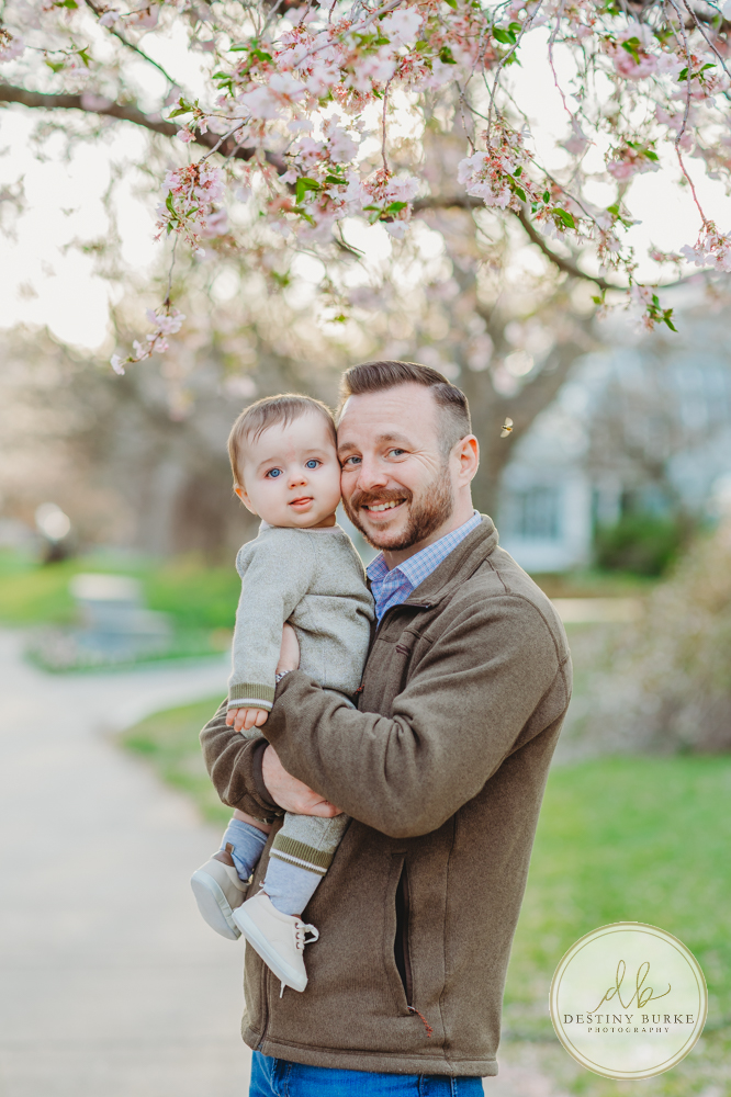 best family photographer near Rochester, NY, at Highland Park, family of 4 under the Cherry Blossom trees, photographed by Caledonia photographer, Destiny Burke Photography at sunset. 6 Month old and 3 year old children with Mom and Dad.