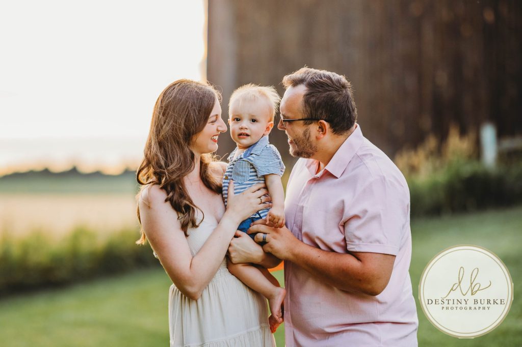 Golden hour extended family photo of the Carson/Ingersoll family in Caledonia, NY, featuring parents, grandparents, and their smiling young child. Captured by Destiny Burke Photography with warm light, candid emotion, and timeless connection.