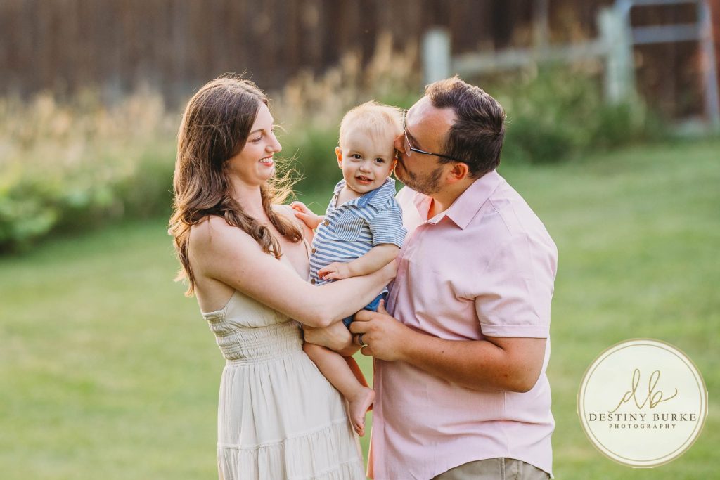 Golden hour extended family photo of the Carson/Ingersoll family in Caledonia, NY, featuring parents, grandparents, and their smiling young child. Captured by Destiny Burke Photography with warm light, candid emotion, and timeless connection.