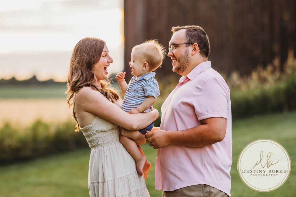 Golden hour extended family photo of the Carson/Ingersoll family in Caledonia, NY, featuring parents, grandparents, and their smiling young child. Captured by Destiny Burke Photography with warm light, candid emotion, and timeless connection.