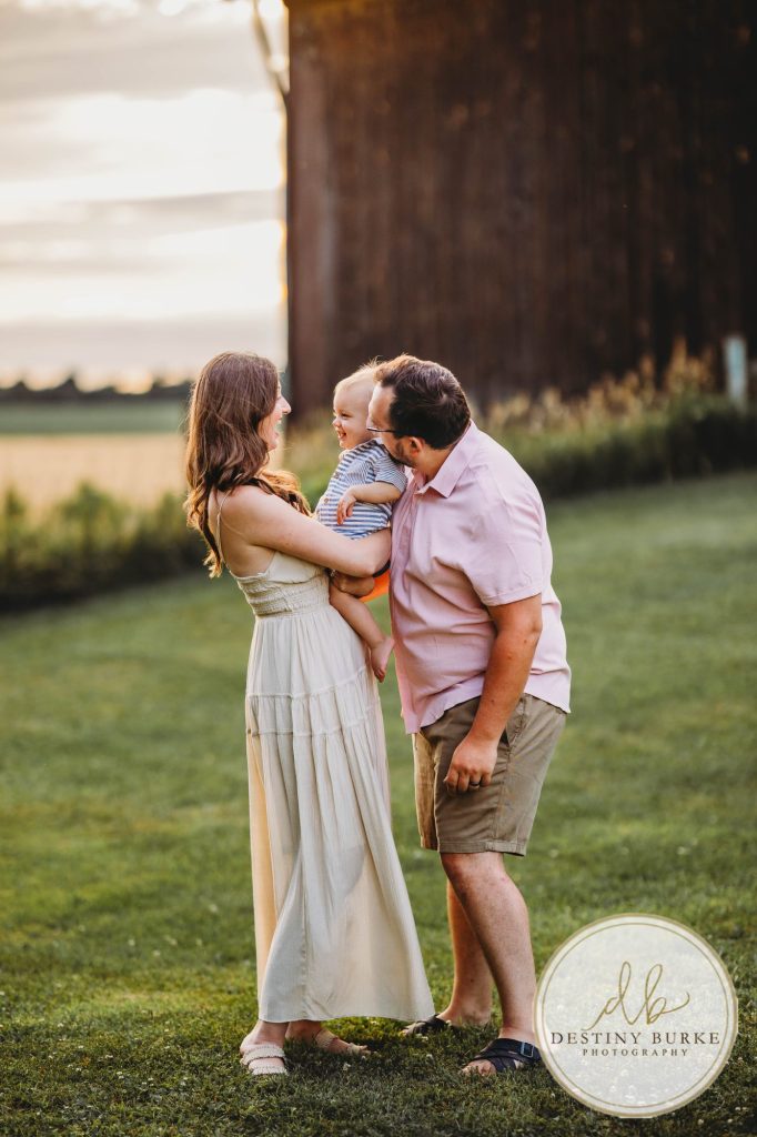 Golden hour extended family photo of the Carson/Ingersoll family in Caledonia, NY, featuring parents, grandparents, and their smiling young child. Captured by Destiny Burke Photography with warm light, candid emotion, and timeless connection.