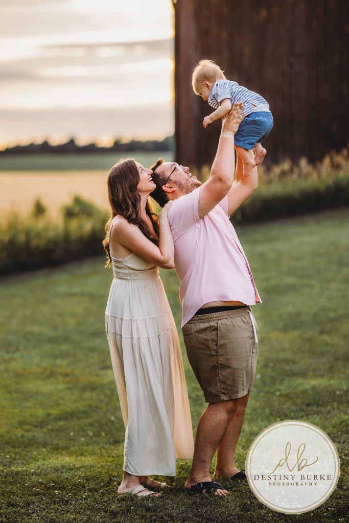 Golden hour extended family photo of the Carson/Ingersoll family in Caledonia, NY, featuring parents, grandparents, and their smiling young child. Captured by Destiny Burke Photography with warm light, candid emotion, and timeless connection.