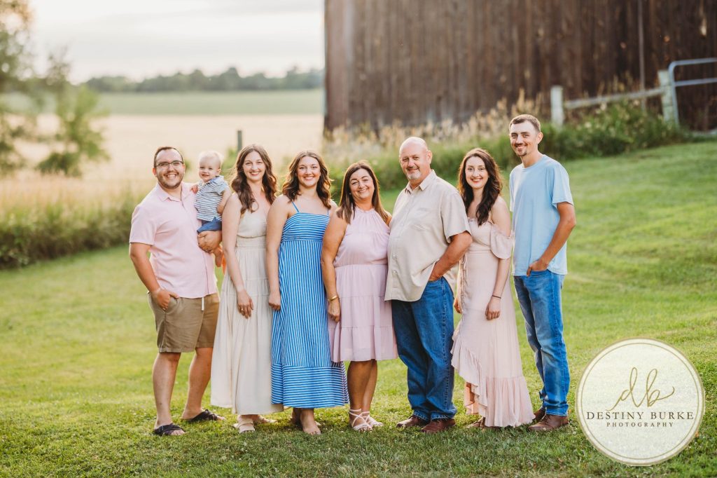 Golden hour extended family photo of the Carson/Ingersoll family in Caledonia, NY, featuring parents, grandparents, and their smiling young child. Captured by Destiny Burke Photography with warm light, candid emotion, and timeless connection.