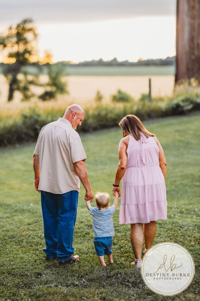 Golden hour extended family photo of the Carson/Ingersoll family in Caledonia, NY, featuring parents, grandparents, and their smiling young child. Captured by Destiny Burke Photography with warm light, candid emotion, and timeless connection.