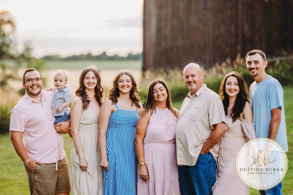 Golden hour extended family photo of the Carson/Ingersoll family in Caledonia, NY, featuring parents, grandparents, and their smiling young child. Captured by Destiny Burke Photography with warm light, candid emotion, and timeless connection.