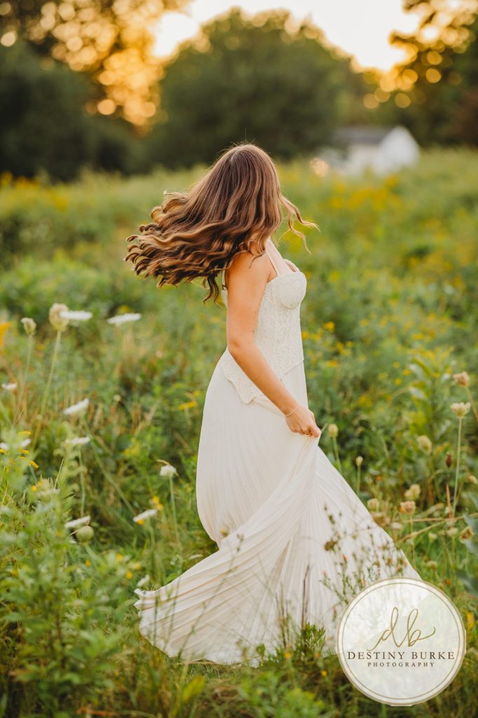 best Senior Portrait Photographer near Rochester, NY at Tinker Park with wildflowers at sunset golden hour