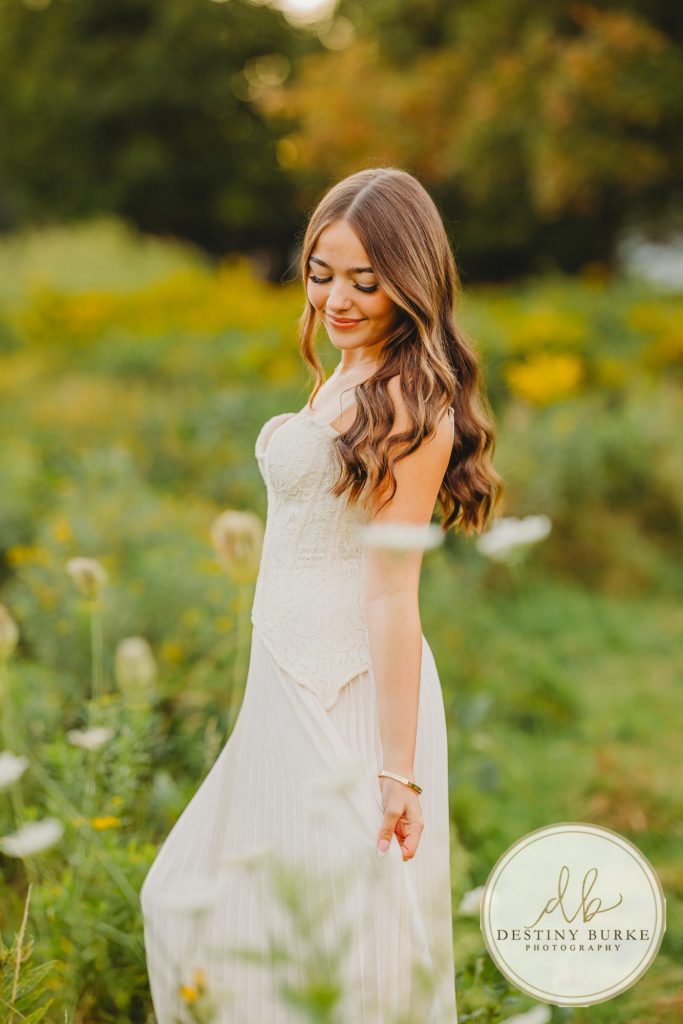 best Senior Portrait Photographer near Rochester, NY at Tinker Park with wildflowers at sunset golden hour